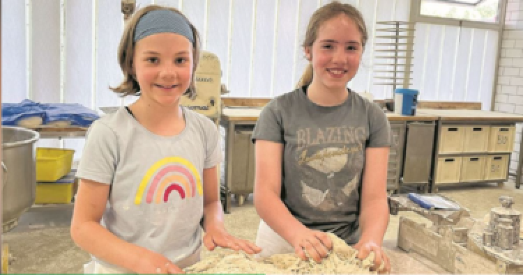 Zwei Schülerinnen formen Croissants und belegen sie mit Schinken, Käse oder Schokolade